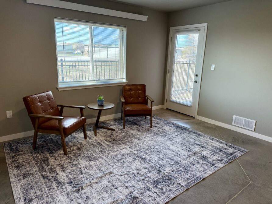 Living room with two leather chairs, round table, and window view