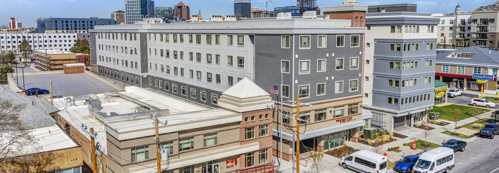 Urban street view with buildings, parked vehicles, and "First Step" sign visible.