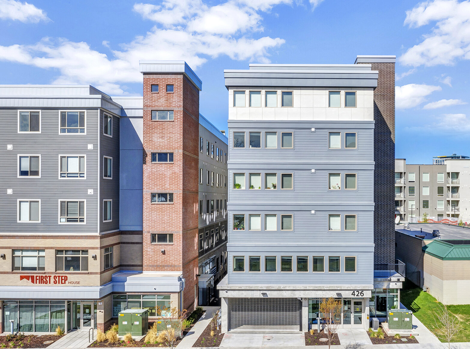 Modern multi-story building labeled "First Step House" with large windows against blue sky