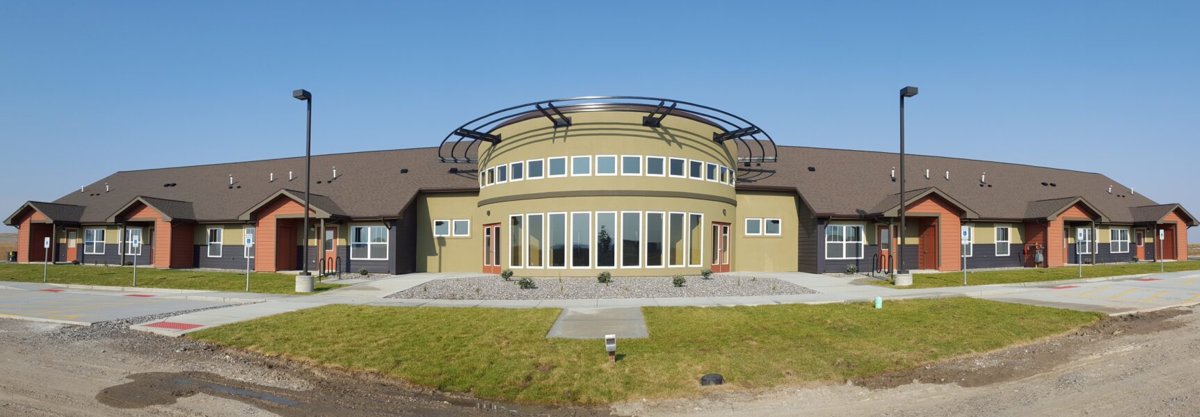 Modern building with circular central section, large windows, and surrounding landscaped area.