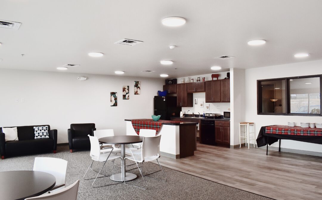Modern communal kitchen with seating area, dark cabinets, and island counter.