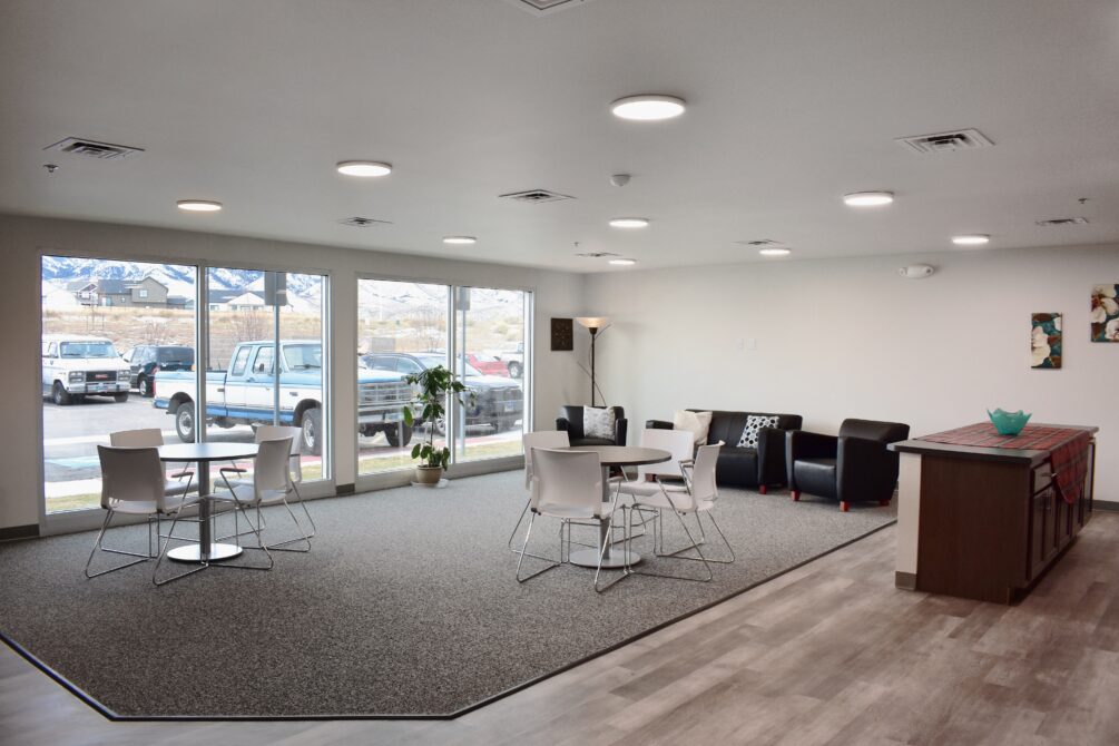 Spacious lounge area with tables, chairs, and couches, featuring large windows with mountain views.