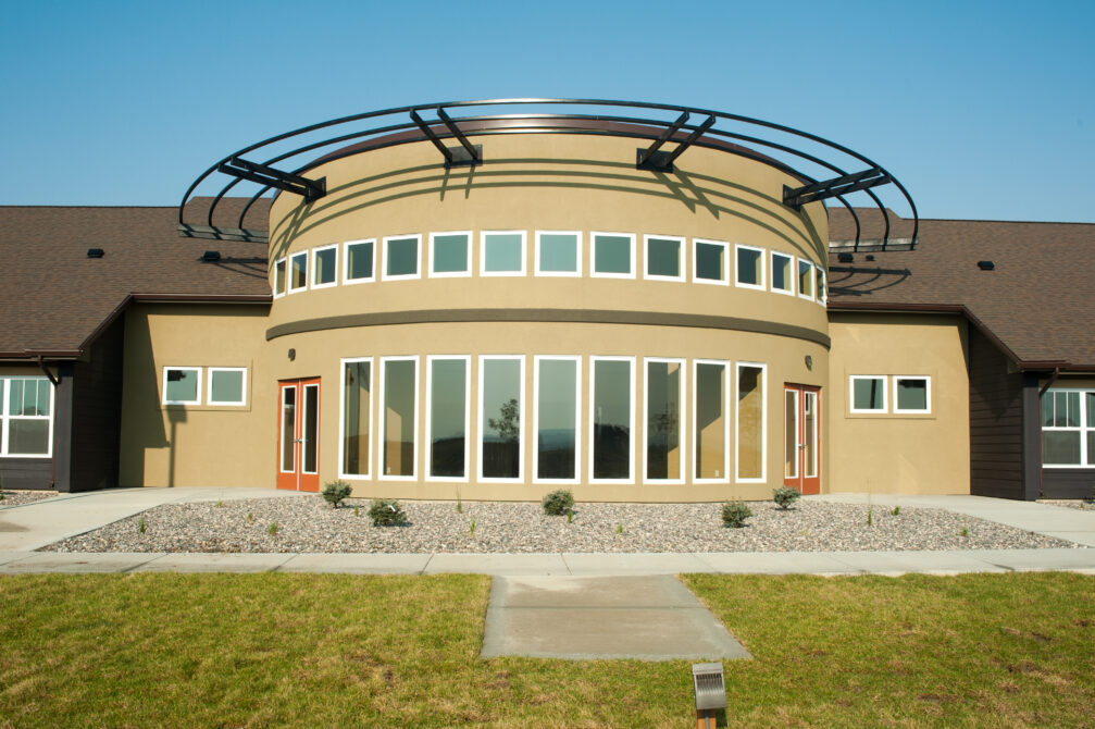 Modern building with a circular facade, large windows, and a distinctive metal awning.