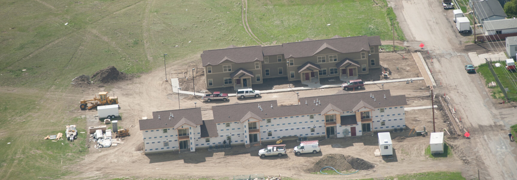 Aerial view of a construction site with two partially completed buildings, vehicles, and construction equipment.