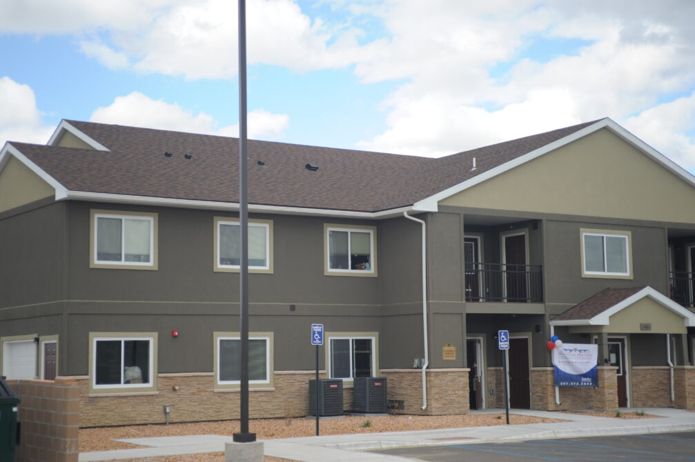 Two-story apartment building with a visible banner and balloons near the entrance.