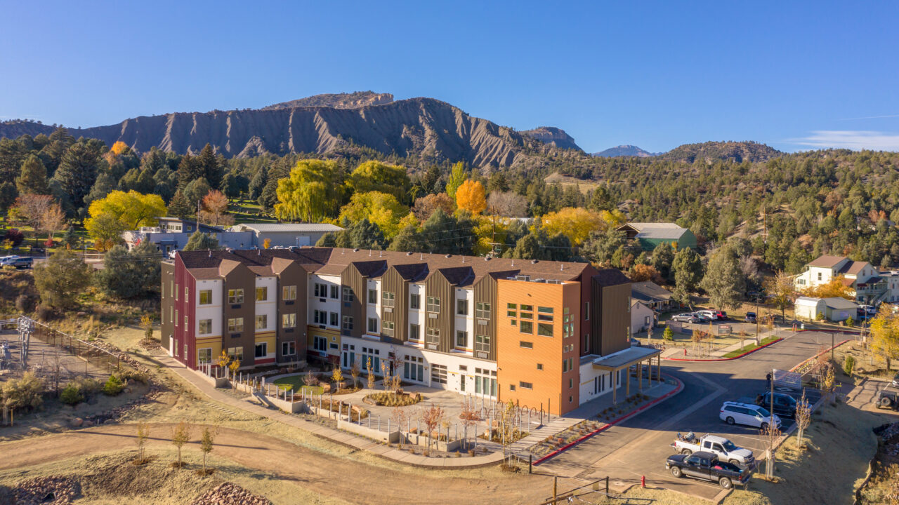 Modern building surrounded by autumn trees and mountains, vibrant landscape