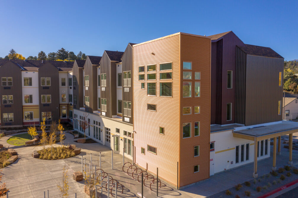 Modern multi-story residential building with varied colors and large windows in a landscaped area