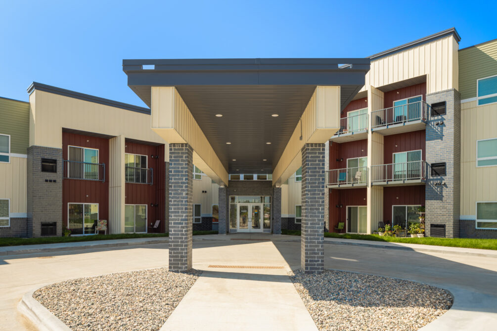 Covered entrance of a modern residential building with balconies and landscaped grounds