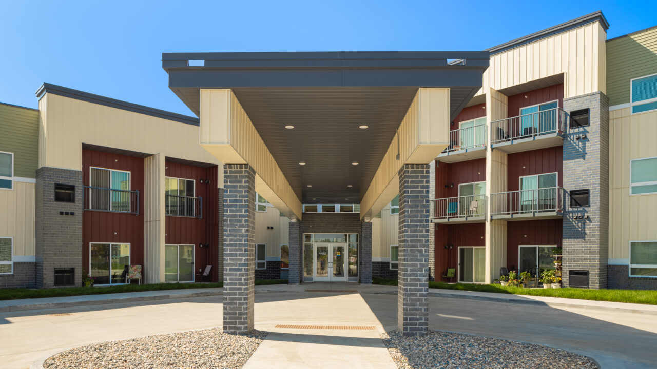 Covered entrance of a modern three-story building with balconies.