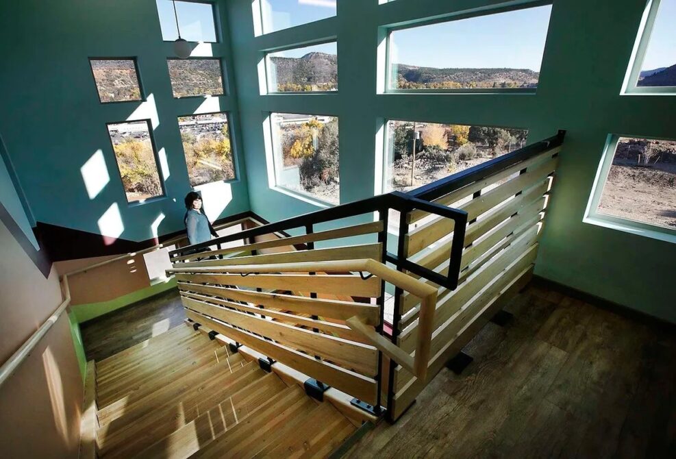 Espero walking down a sunlit staircase with mountain views through modern windows