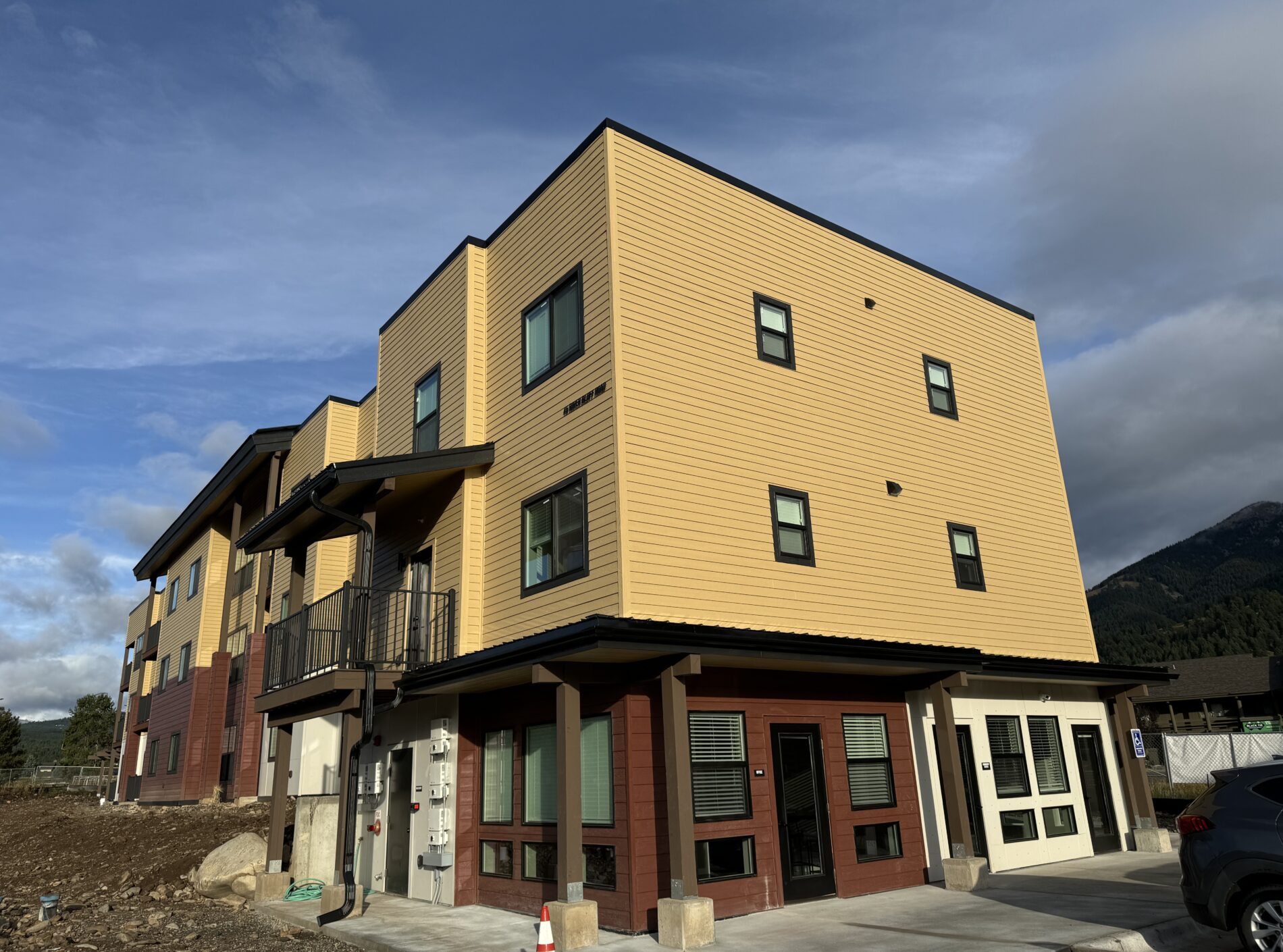 Modern three-story yellow building with multiple windows and mountain background