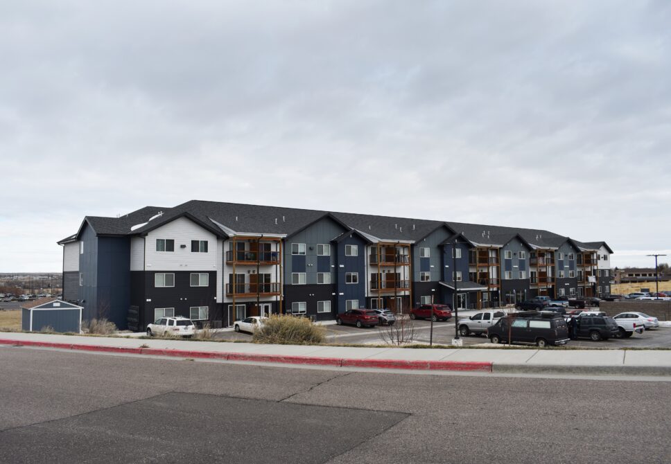 Apartment complex with multiple floors and parked cars in front
