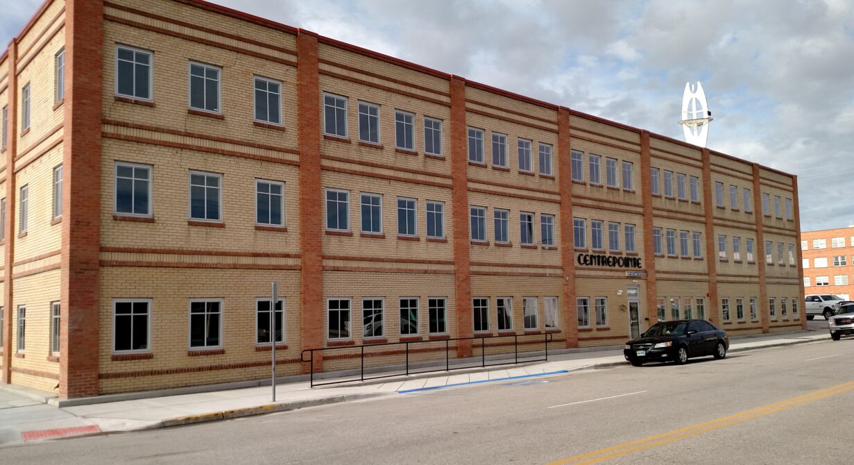 Three-story brick building labeled "Centrepoint," with cars parked in front on a cloudy day.