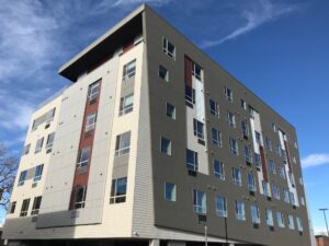 Modern multi-story apartment building with geometric design under clear blue sky