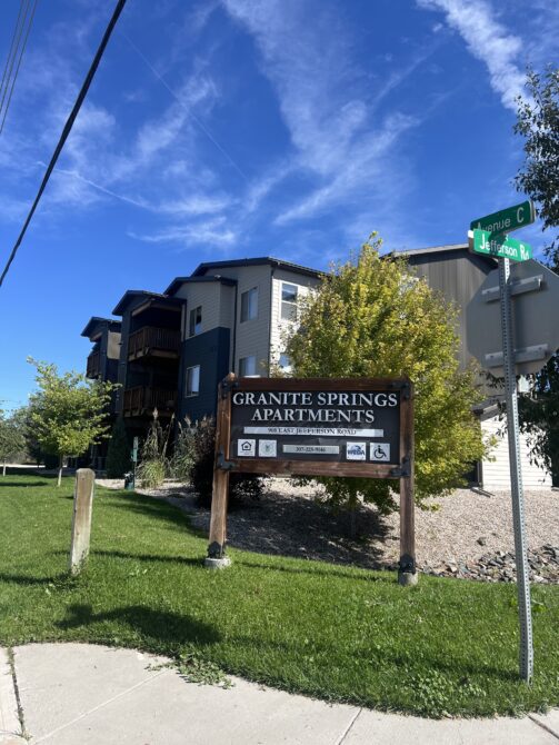 Granite Springs Apartments sign near corner of Avenue C and Jefferson Rd with trees and buildings in the background.