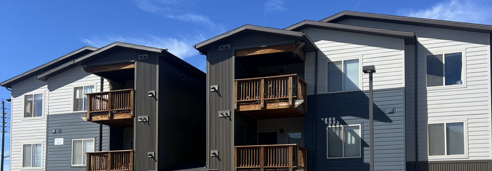 Modern apartment building with wooden balconies under a clear blue sky