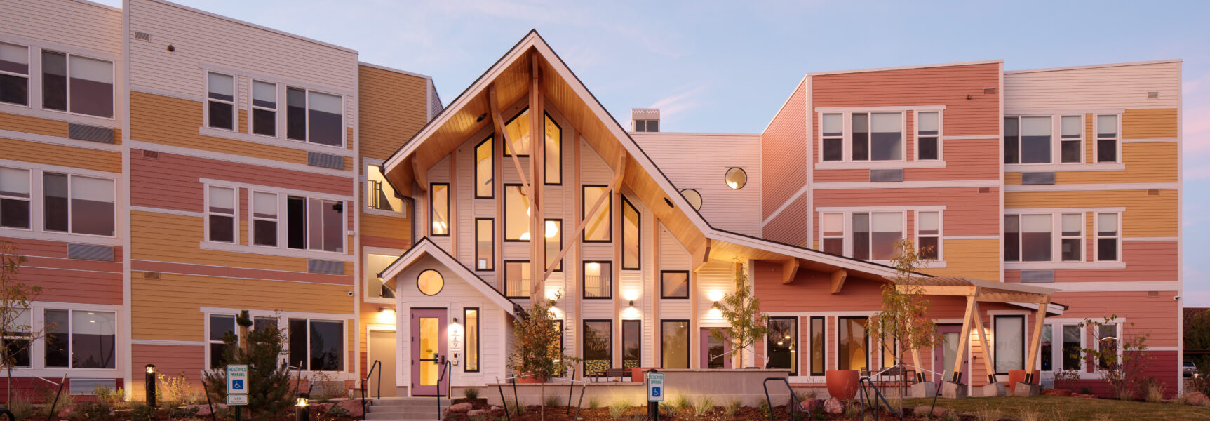 Laurel House exterior with colorful facade, multiple windows, and warm lighting, set against a blue sky at dusk