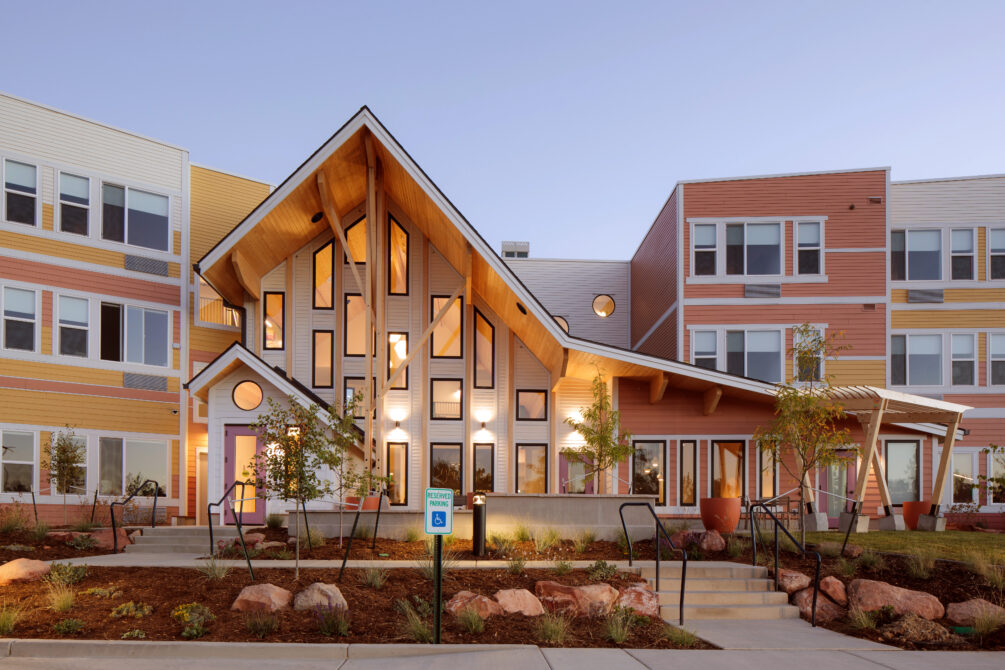 A modern architectural exterior of Laurel House with large wooden beams, vibrant color accents, and a "Reserved Parking" sign.