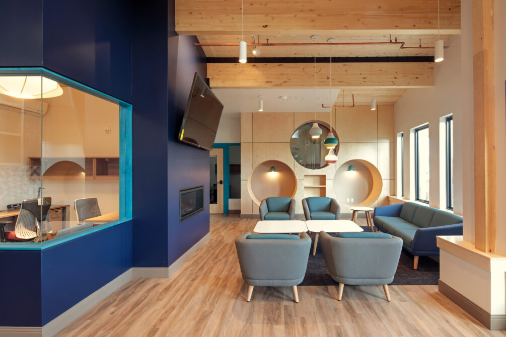 Modern lounge with blue walls, wooden ceiling, and stylish furniture