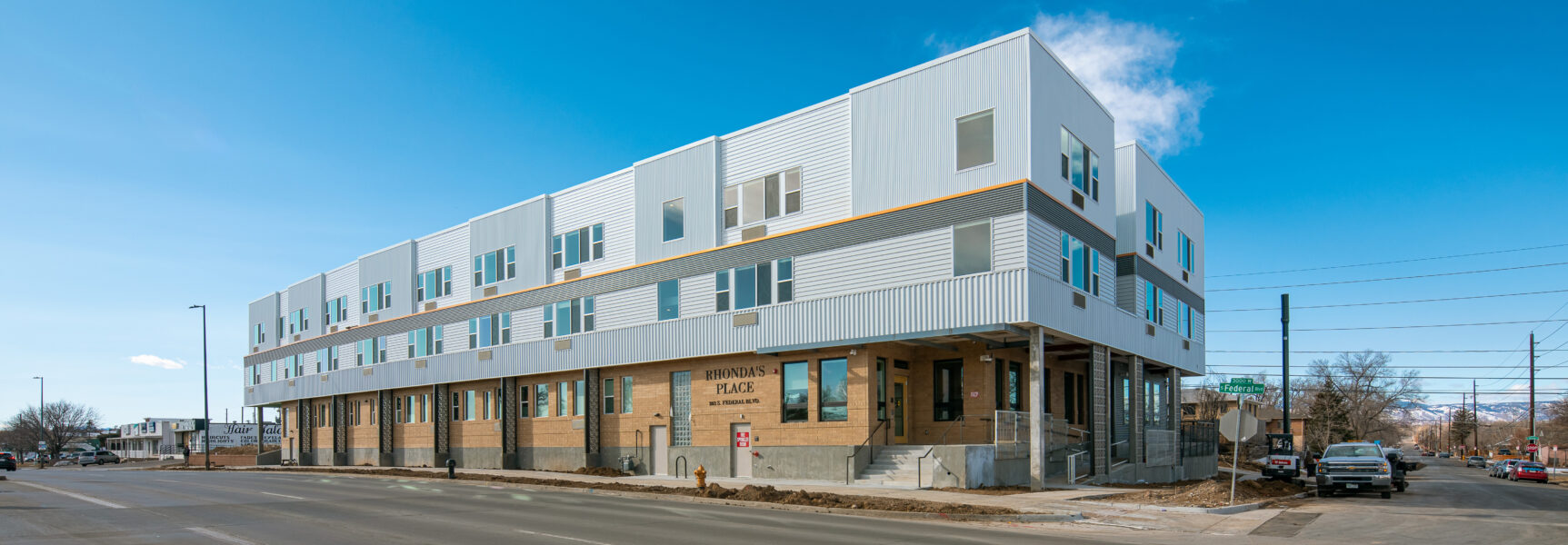 Rhonda's Place building, corner view, three-story modern structure with large windows, clear blue sky