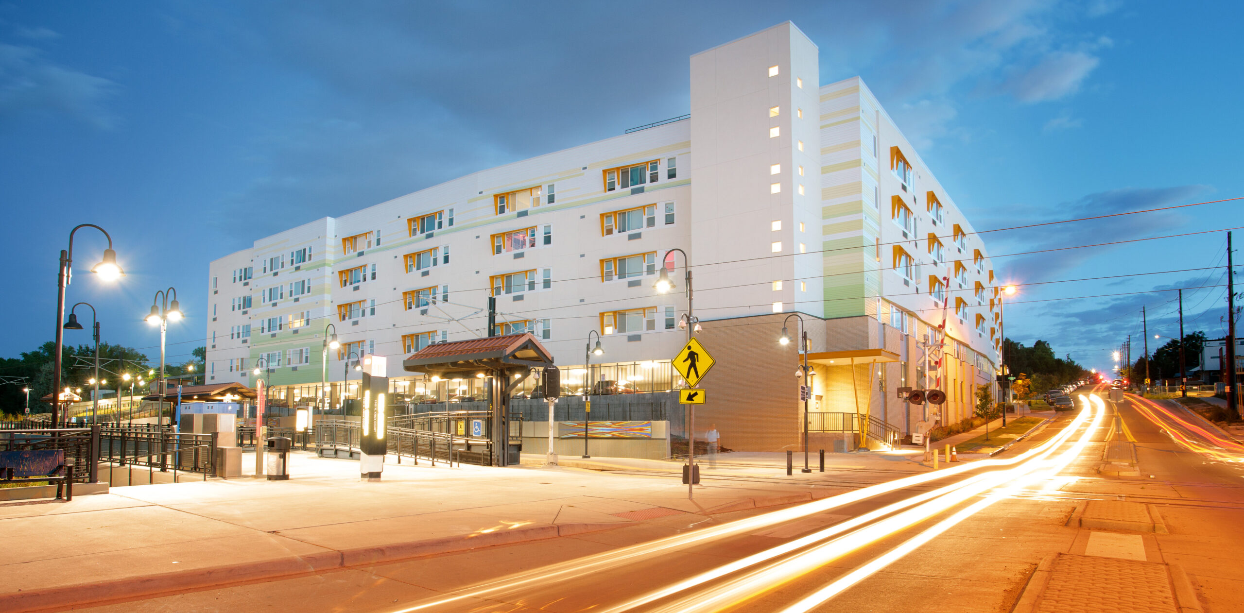Modern multi-story building at dusk with streetlights and a walkway.