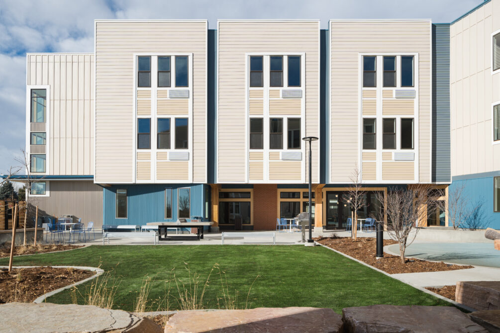 Modern three-story building with large windows and landscaped courtyard.