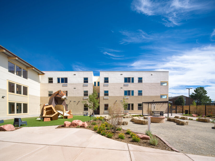 Modern building courtyard with sculpture, landscaped garden, and clear blue sky