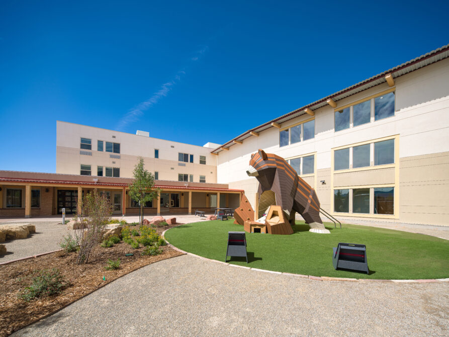School courtyard with large bear sculpture and surrounding garden.