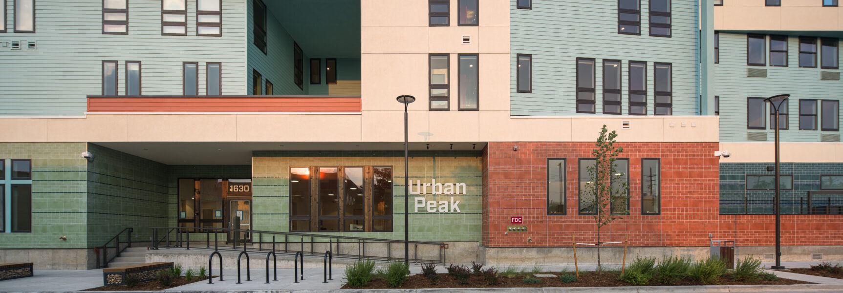 Front entrance of Urban Peak building, featuring modern design, green facade, and large windows.