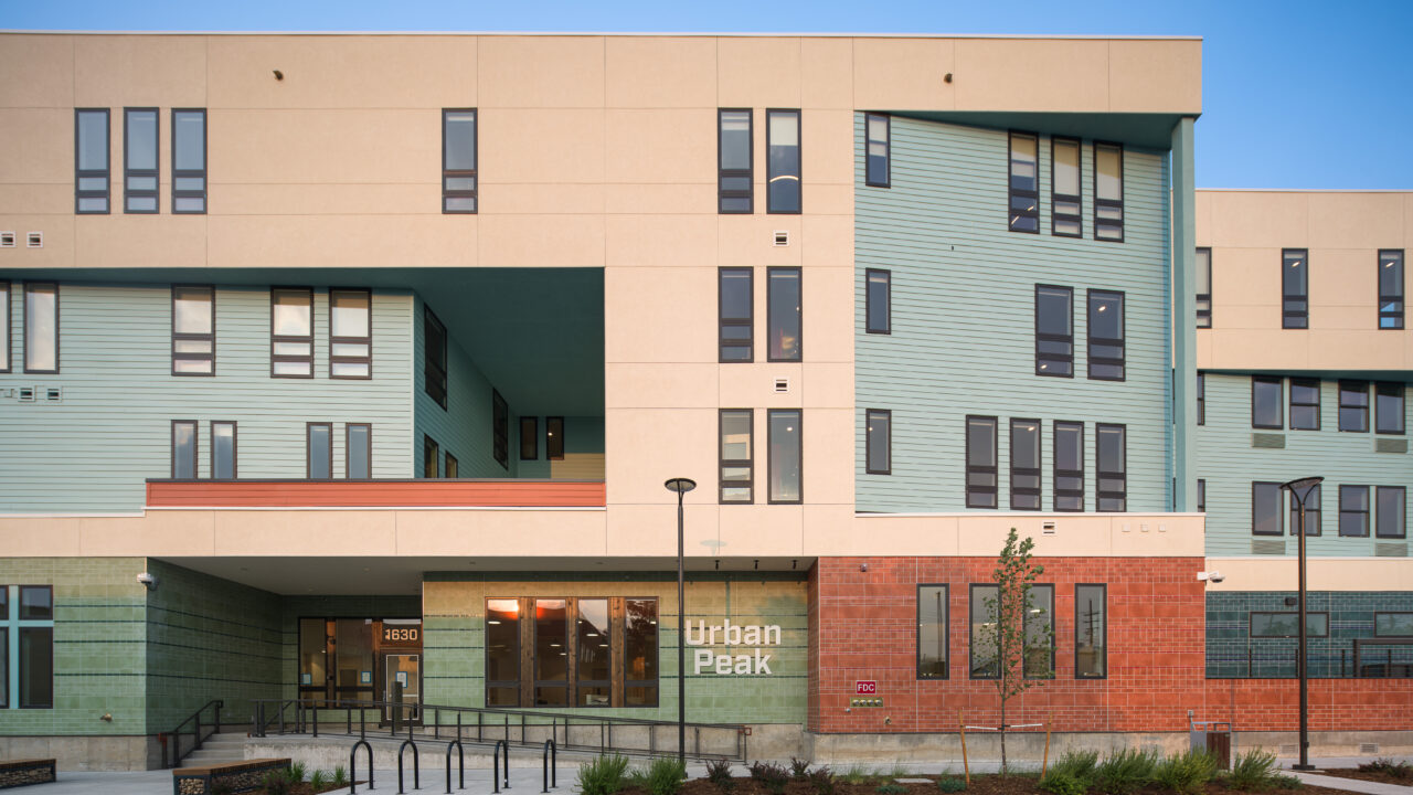 Modern building with green and red facade, labeled "Urban Peak" at entrance.