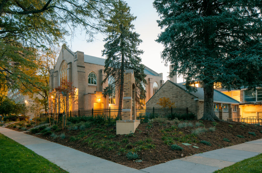 Church building surrounded by trees, pathways, and soft evening lighting.