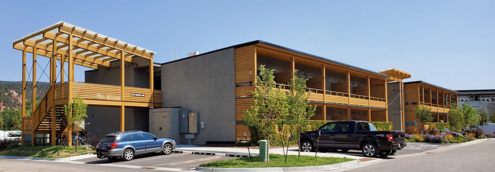Modern building with wooden accents, parked cars, and "2055 Dolores Way" sign.