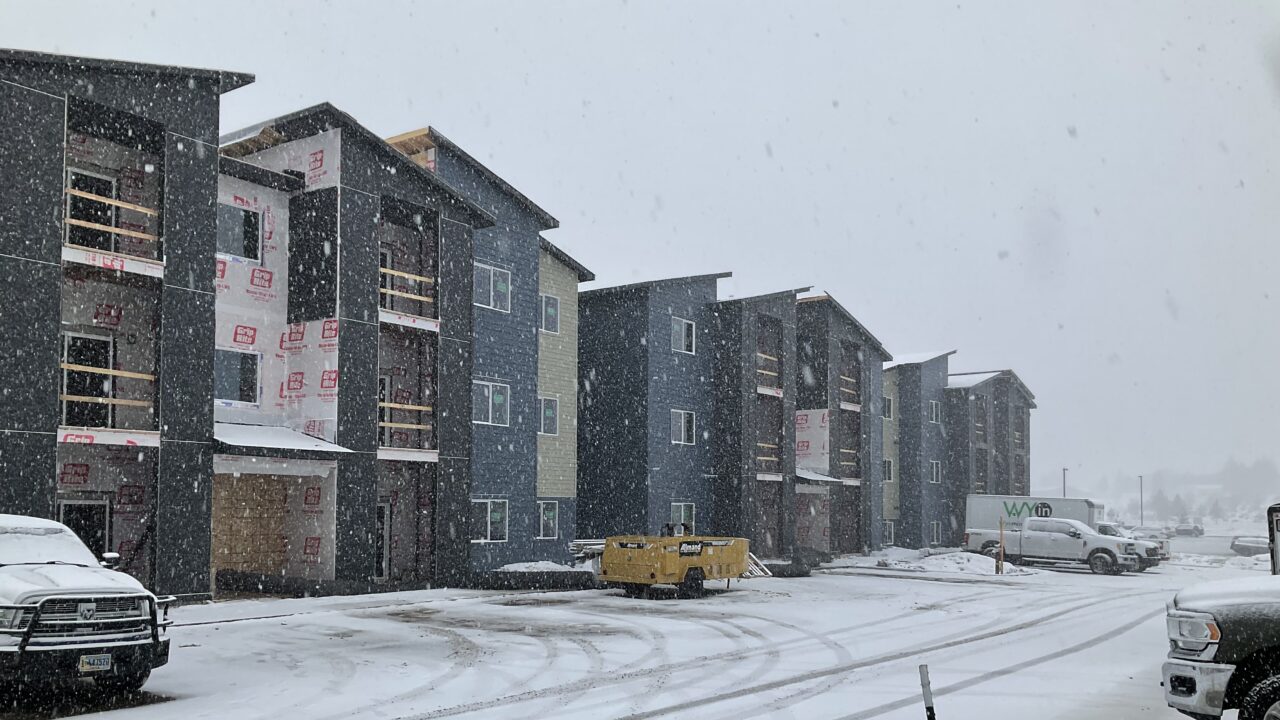 Snow-covered construction site with partially built apartment buildings and vehicles.