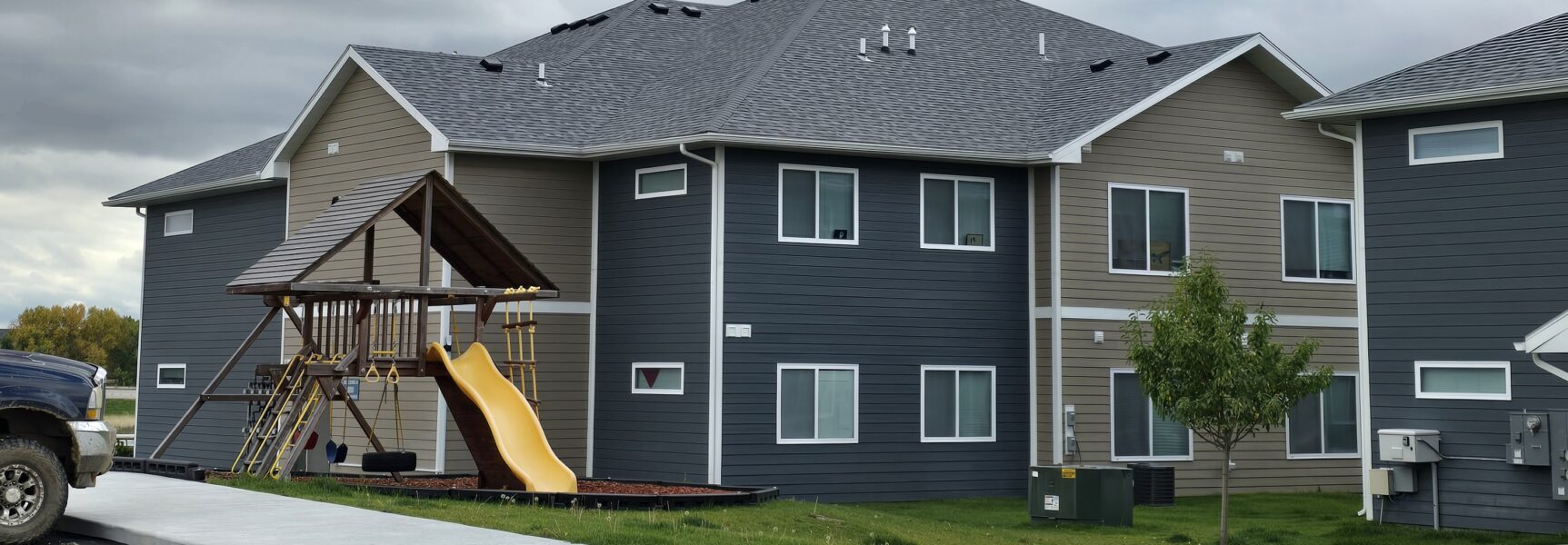 Cloudy sky over apartment building with playground slide.