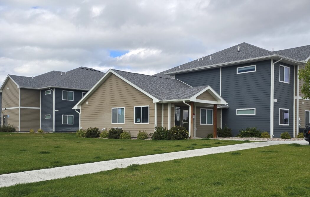 Residential houses with beige and gray siding, overcast sky
