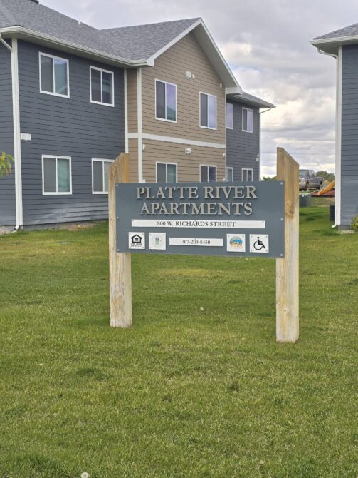 Platte River Apartments sign at 800 W. Richards Street, near two-story buildings.
