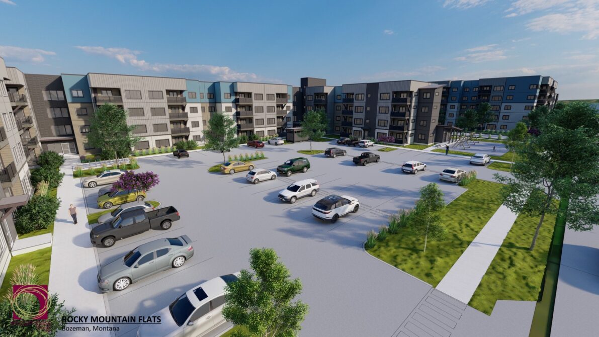 Rocky Mountain Flats apartment complex with parking lot, trees, and sunny sky in Bozeman, Montana