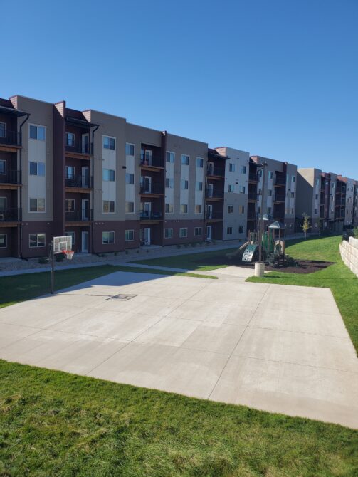 Basketball court and playground in front of multi-story apartment building