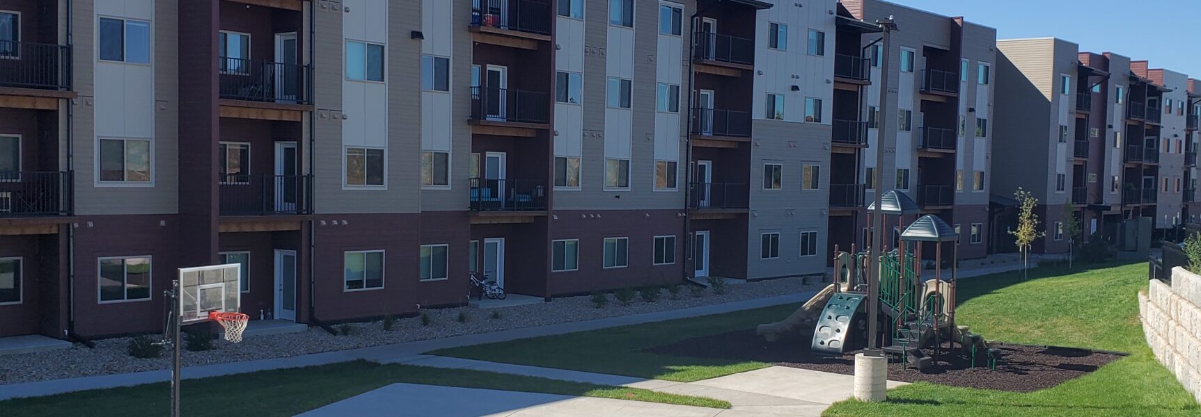 Basketball court and playground in front of multi-story apartment building