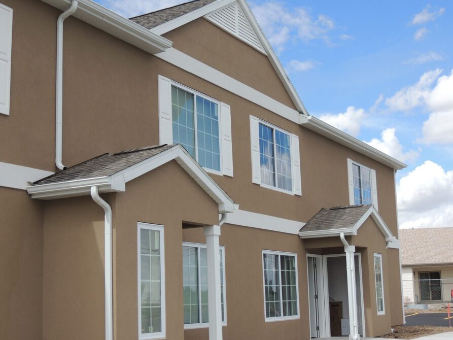 Brown two-story house with white trim and multiple large windows