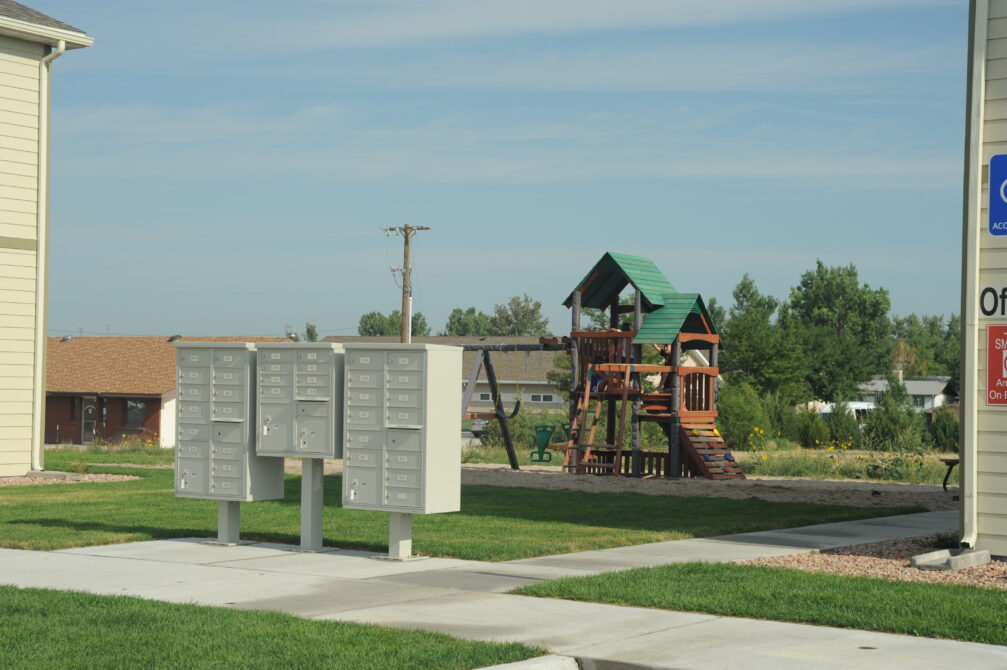 Communal mailboxes and playground near residential area with green lawn