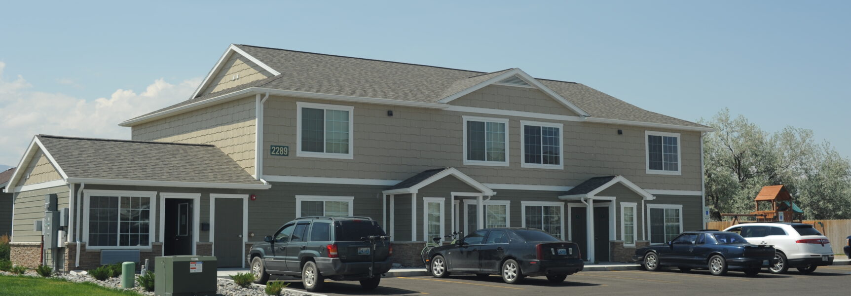 Duplex with multiple cars parked, house number "2289", and a playground in the background