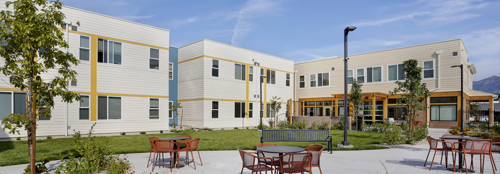 Courtyard with tables, chairs, and landscaped garden at a modern residential building