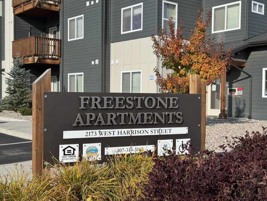 Freestone Apartments entrance sign, address 2173 West Harrison Street, with fall foliage in front of apartment building