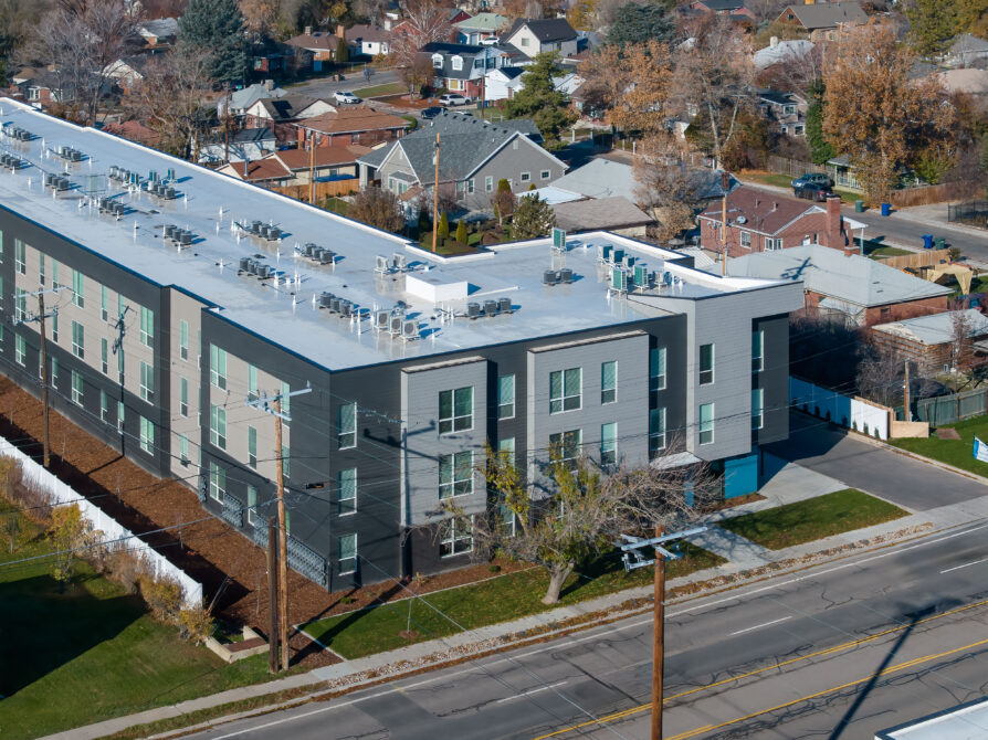 Aerial view of a modern, three-story building surrounded by suburban homes.