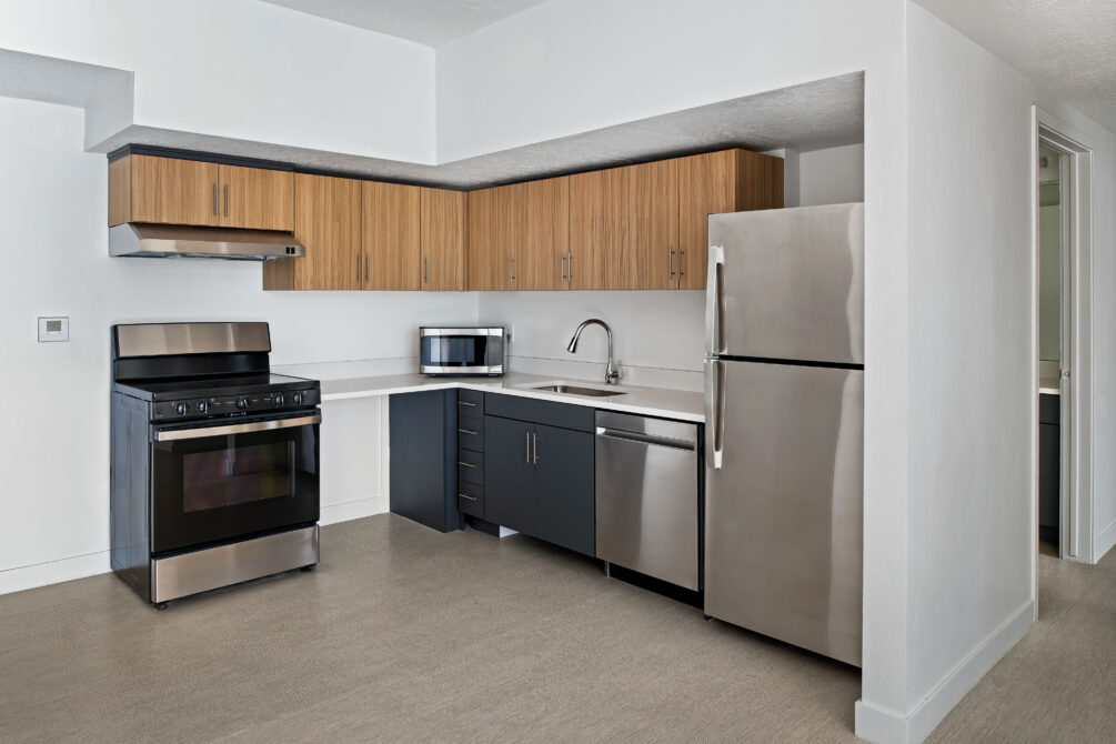 Modern kitchen with stainless steel appliances, wood cabinets, and a microwave on the counter.