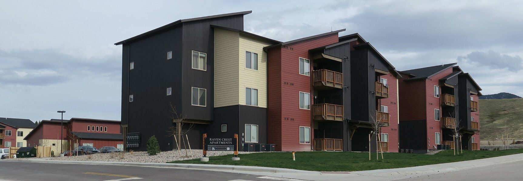 Raven Crest Apartments building with multiple floors, modern design, and wooden balconies in a suburban setting