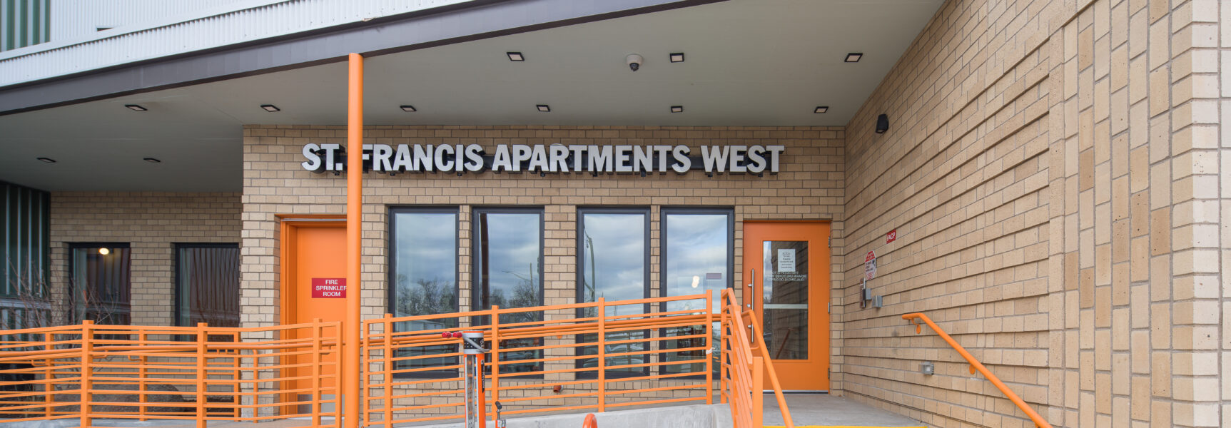 Entrance to St. Francis Apartments West with orange railings and stairs