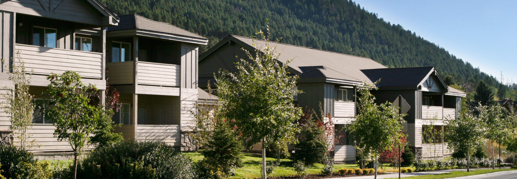 Residential buildings with wooden balconies surrounded by trees and mountains.