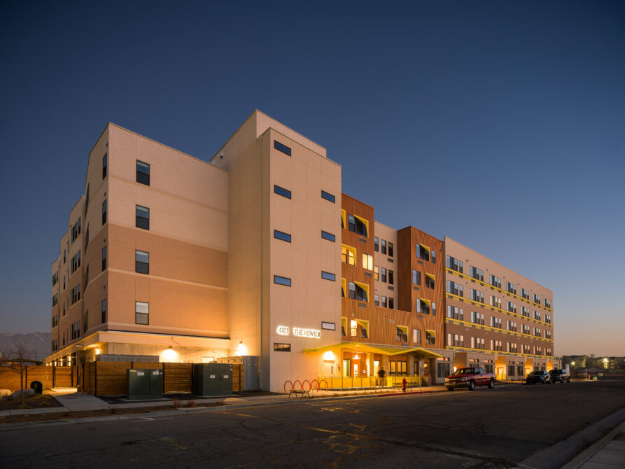 Urban residential building at dusk, with warm lighting.